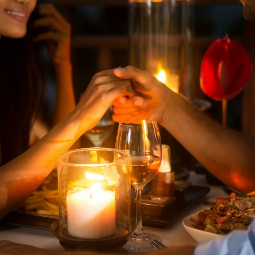 Romantic couple holding hands together over candlelight during romantic dinner